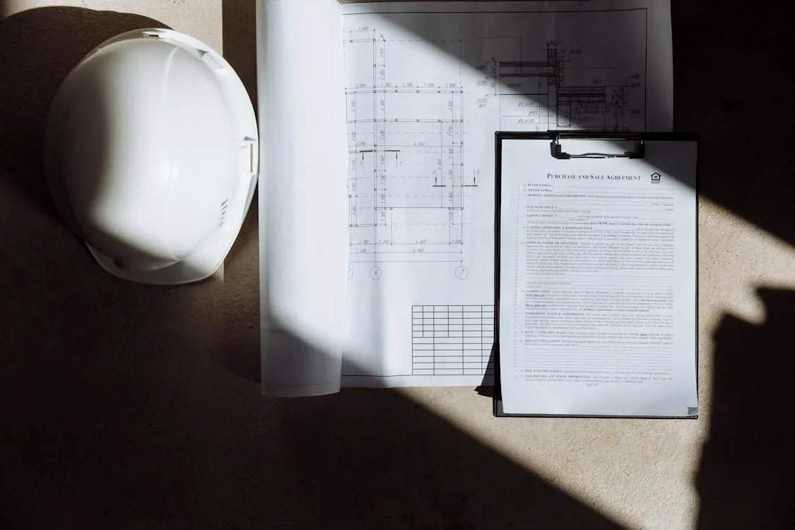 white hard hat, floor plans and sale agreement paperwork